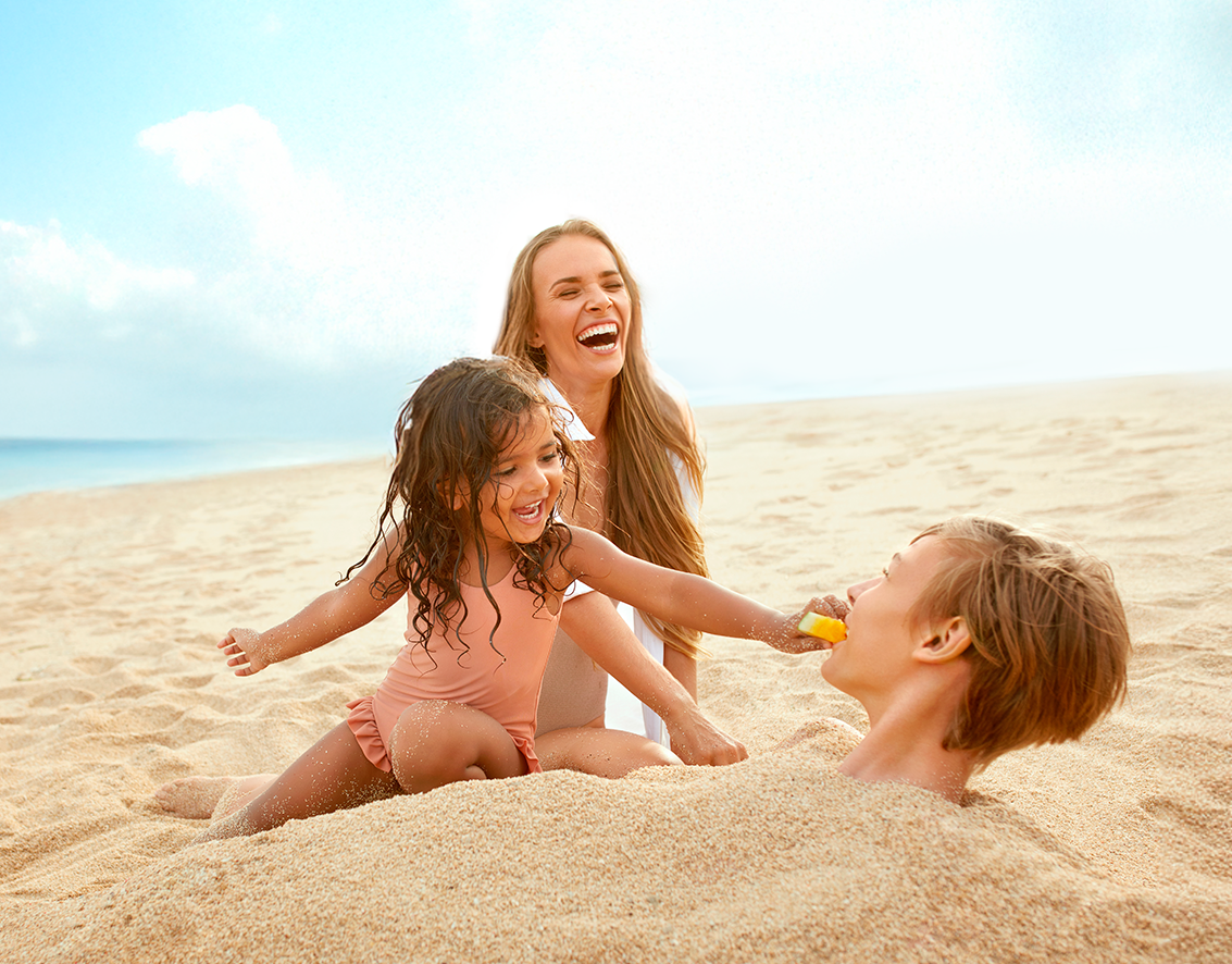 Mamá e hijos, riendo en la playa del hotel Sensira en Riviera maya, Mexico