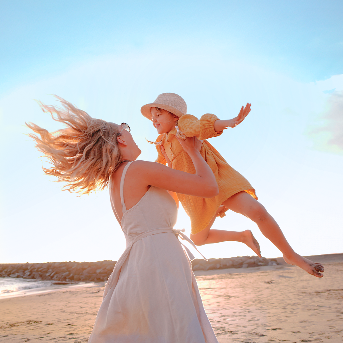 Mamá e hija, jugando en la playa, junto al mar.