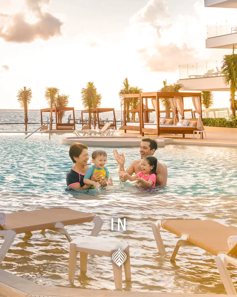 Familia jugando en alberca al aire libre con vista al mar y ambiente tropical.